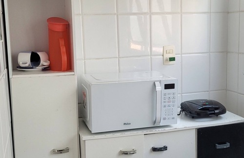 Mongagua Apartment | Apartamento moderninho, com sacada de frente para o mar. Sala bem iluminada.