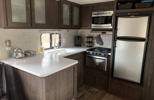 Modern RV camper with all the perks nNestled in tree at lake edge
