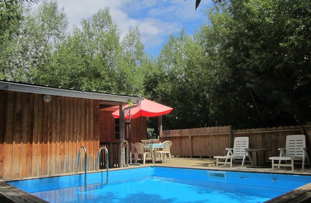 Wooden lodge with terrace and swimming pool in a green setting